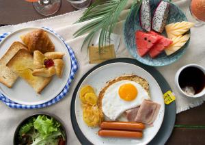 奈通海滩Naithonburi Beach Resort - SHA Extra Plus的一张桌子,上面放着两盘食物,包括鸡蛋和烤面包
