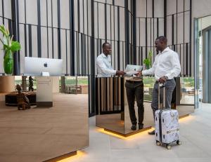 阿比让Noom Hotel Abidjan Plateau的两个人站在大厅里,拿着一个手提箱