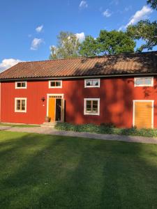 萨拉Albäck Gård Bagarstugan - Granne med Sala Golfklubb的前面有绿色草坪的红色房子