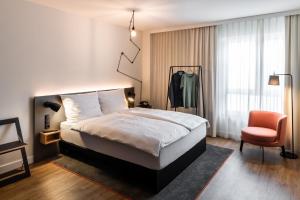 威斯巴登pentahotel Wiesbaden的配有一张床和一把椅子的酒店客房