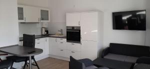 阿尔特费尔Apartment 10 in Altefähr am Strelasund的厨房配有白色橱柜、桌子和电视。