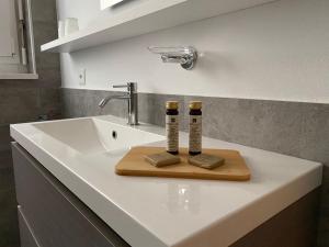 卢加诺APNC Apartment Castagnola的浴室水槽和木板上的2瓶水