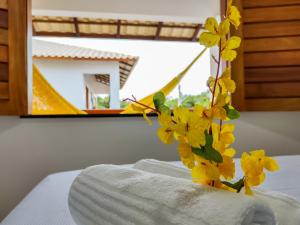 日若卡-迪热里科阿科阿拉Pousada Brisas的床上方的花瓶,有黄色的花朵