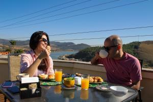 卡皮托利乌Pousada Quintal da Lua的坐在餐桌上吃早饭的男人和女人