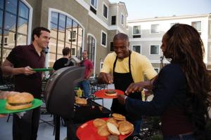 格伦代尔Staybridge Suites Phoenix Glendale Sports Dist, an IHG Hotel的一群人在烧烤架上准备食物