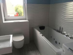 富伦多夫"Segelboot"的白色的浴室设有卫生间、浴缸和窗户。