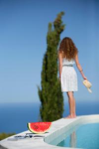 苏卡雷斯Boo Premium Living Villas的一个女人站在一个游泳池旁边,一边吃西瓜片