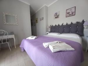 萨包迪亚Il Grifo的一间卧室配有一张紫色床和毛巾