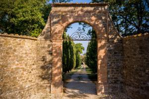 蒙塔尔奇诺Villa Le Prata - Farm House & Winery - Adults Only的拱门,拱门,砖墙上方有树木