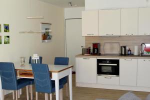 奥茨塞巴德·迪尔哈根Seeschwalbe App 34的厨房配有白色橱柜、桌子和蓝色椅子