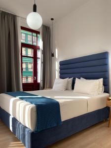 塞萨洛尼基The Maroon Bottle Luxury Suites的一间卧室配有一张大床和蓝色床头板