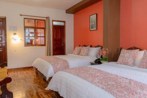 基多Rincón Familiar Hostel Boutique的橙色墙壁客房的两张床