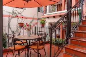 基多Rincón Familiar Hostel Boutique的阳台配有桌椅和遮阳伞