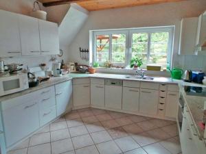 Hanerau-HademarschenDrengenberg的一间厨房,配有白色的橱柜和大窗户