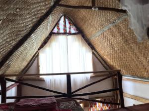 波特尔堡Kalitusi Nature Resort的稻草屋顶的窗户,带窗帘