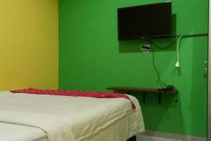 TjolomaduRedDoorz near Bandara Adi Soemarmo Solo的一间卧室设有绿色的墙壁、一张床和电视