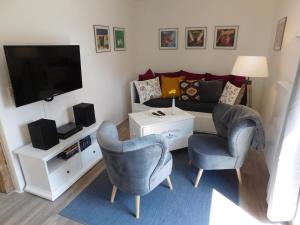 Bad SülzePfarrscheune的客厅配有沙发、两把椅子和电视