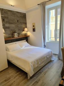 安齐奥Christy Suite Elegante appartamento nel centro storico di Anzio的卧室配有一张白色大床和砖墙