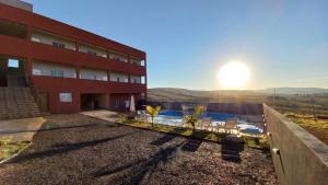 卡皮托利乌Pousada Morada dos Pássaros的红色的建筑,设有游泳池,享有日落美景