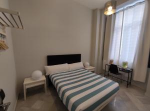 塞维利亚New Samay Hostel的一间卧室配有带条纹毯子的床