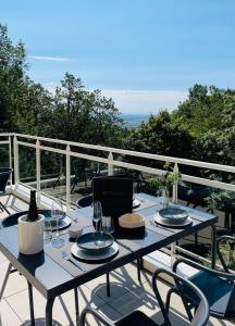埃圭斯海姆Hotel SPA Husseren Collections - Proche Colmar - Eguisheim的阳台上的桌子上摆放着盘子和酒杯