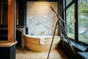 阿姆斯特丹Boutique Hotel The Noblemen的一个带望远镜的浴室内的大型木制浴缸