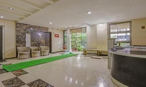 孟买Treebo Trend Welcome Apartments的大堂设有带椅子和绿色地毯的酒吧