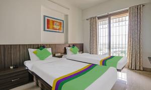 孟买Treebo Trend Welcome Apartments的带窗户的客房内的两张床