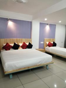 埃尔讷古勒姆The White Orchid Luxury Service Apartments的一间卧室配有两张带红色和黑色枕头的床
