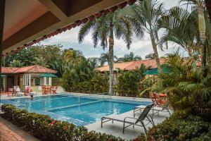 比亚维森西奥Hotel Paloverde Villas Campestres的一个带椅子的游泳池,棕榈树