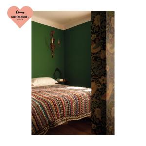 艾马维尔Maison Coromandel的一间卧室设有一张带绿色墙壁的床