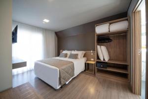 格拉玛多Gramado Resort Apart的卧室设有一张白色大床和大窗户