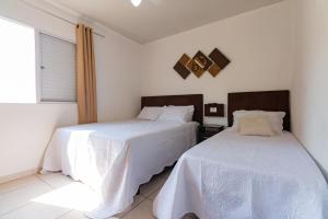 圣保罗Brás - APARTAMENTO ACONCHEGANTE的一间卧室设有两张带白色床单的床和窗户。