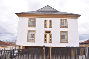 伊巴丹AYAAKAJE GUEST HOUSE的一间白色房子,在栅栏后面设有棕色的窗户