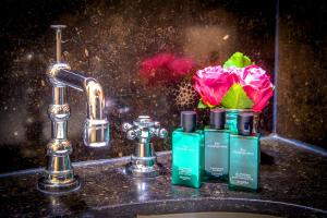 布鲁日河滨之家 - 豪华旅馆的水槽,有两瓶肥皂和一朵花