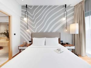 迪拜Adagio Premium The Palm的卧室配有白色的床和条纹墙