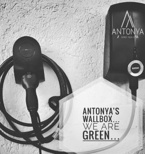 思科纳Antonya Apartments的插入带有标志的墙上的用电充电器