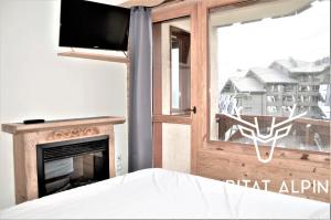 葱仁谷Apartment ski in/out Val Thorens的一间卧室设有壁炉、电视和窗户。