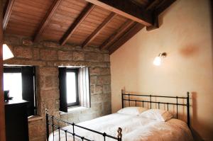 FolgosinhoCasa dos Limos Verdes的石墙客房的卧室配有一张床