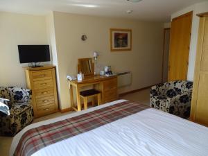 布里村The Sands Hotel, Orkney的一间卧室配有一张床和一张书桌及电视