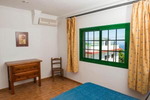 弗龙特拉Apartamentos la Palmera的一间卧室设有绿色窗户和一张书桌