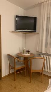 奥彭海姆Hotel Gold´ne Krone的一间设有一张桌子和两把椅子的房间,墙上设有一台电视机