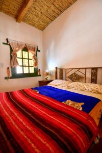 胡阿卡勒拉Hosteria la granja的一间卧室配有一张带红色毯子的床