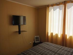 拉塞雷纳Departamento Amoblado a Pasos del Faro的卧室配有一张床,墙上配有电视。