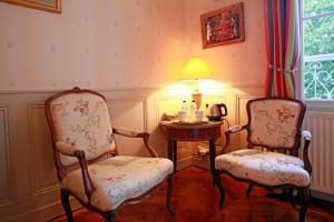 昂热马蒂尔德尚布尔酒店的一间设有两把椅子和一张带台灯的桌子的房间
