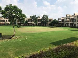 马尼萨Premium Apartment in Tarudhan Valley Golf Resort的一座绿色高尔夫球场和一些建筑