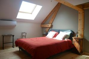 Pommiers-en-Forezchambre d hôte La Grange的一间卧室配有一张红色大床和天窗