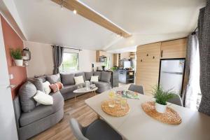 莱马特Mobile home 3 chambres 2 salles de bains dans camping 4 étoiles aux charmettes MH k168的客厅配有沙发和桌子