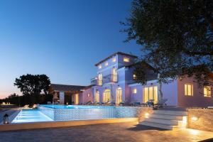 伊奥斯克里克斯Aneli Luxury Villas - Villa Alexandra的一座晚上设有游泳池的房子