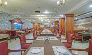 迈索尔Treebo Trend Komfort Suites 3 Km From Mysore Palace的用餐室配有长桌子和红色椅子